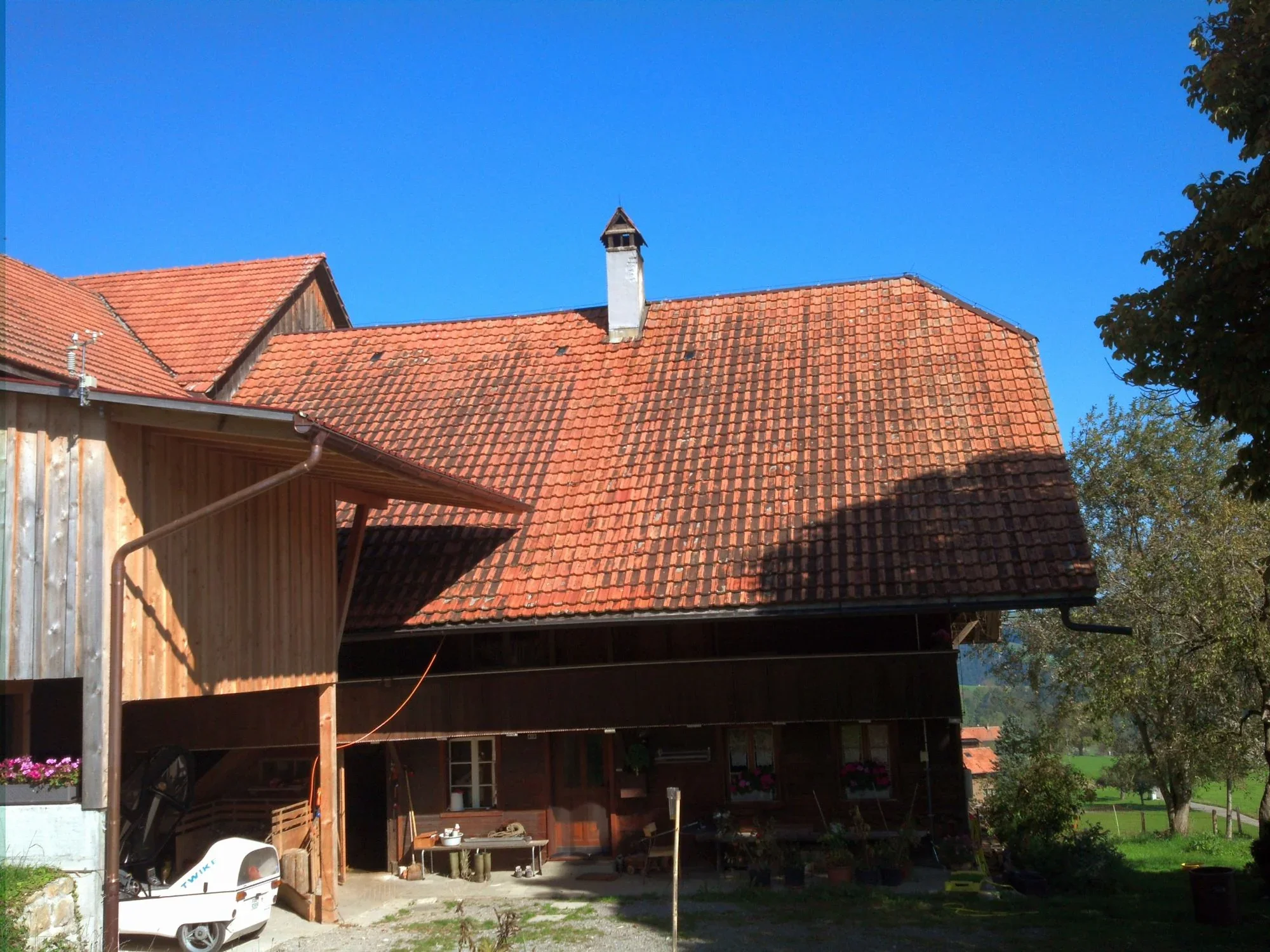 Der Obere Riedacker: Bauernhaus mit Ziegeldach und Kamin unter blauem Himmel